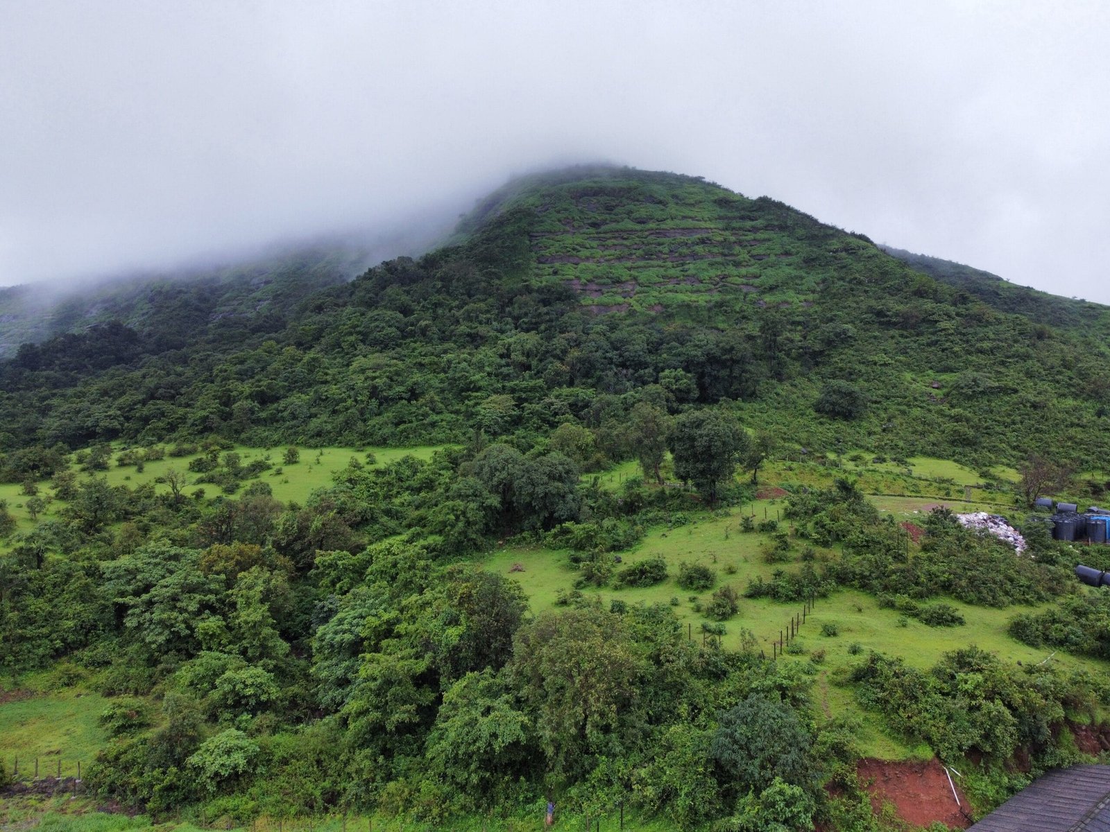 Aerial view of a lush green resort surrounded by mountains and a serene lake in the background.