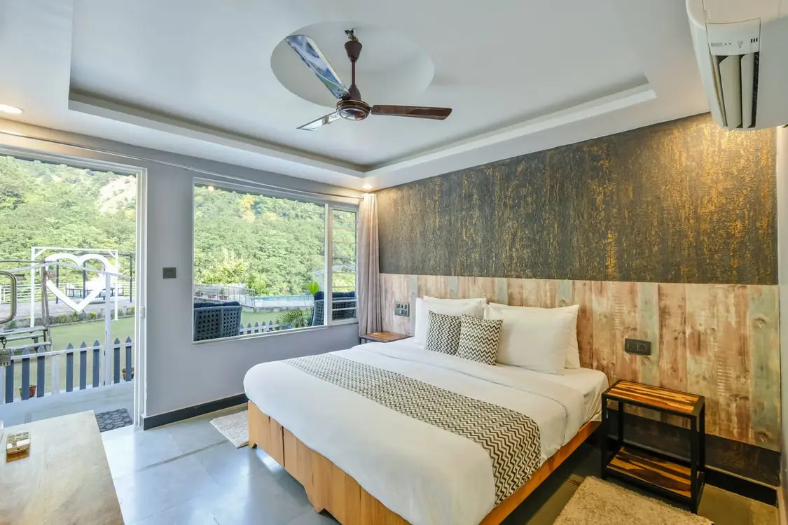 Luxurious hotel room with a cozy bed and large windows offering a breathtaking view of the mountains.